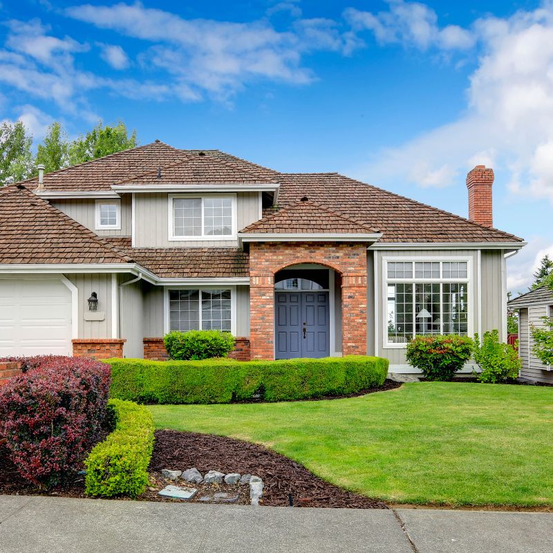 a large house with a lush lawn with a clear blue sky behind it